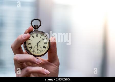 Il tempo passa vicino: L'uomo sta tenendo un orologio d'annata nella sua mano, contesto di affari, spazio di copia Foto Stock