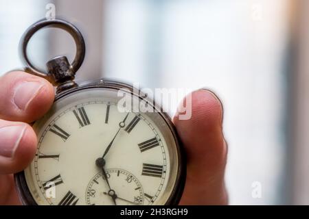 Il tempo passa vicino: L'uomo sta tenendo un orologio d'annata nella sua mano, contesto di affari, spazio di copia Foto Stock