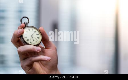 Il tempo passa vicino: L'uomo sta tenendo un orologio d'annata nella sua mano, contesto di affari, spazio di copia Foto Stock