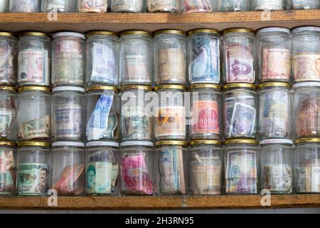 Valute mondiali attualmente in uso o obsolete. Banconote poste in vasetti di vetro. Numismatica è la raccolta di monete o banconote. Foto Stock