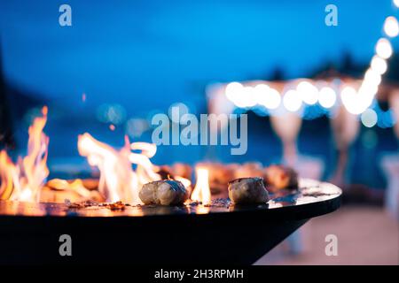 Primo piano di filetti di pesce su una griglia a forma di ciotola con un foro di fuoco al centro. Foto Stock