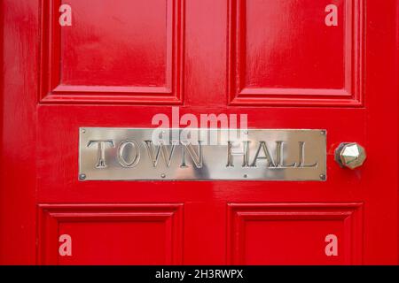 Town Hall segno di metallo argento. Cartello in acciaio cromato lucido su porta in legno rosso brillante, manico in acciaio inossidabile lucido e pulito. Lettere maiuscole municipio Foto Stock