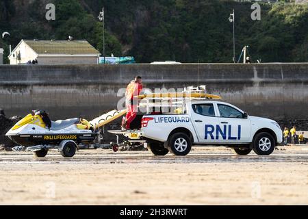 23.10.2021 - Newquay, Cronwall. RNLI Lifeboat a quattro ruote motrici 4x4 parcheggiato sulla spiaggia di sabbia guardando i surfisti per garantire che siano pronti a salvare la nuotata Foto Stock