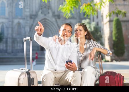 Coppia di viaggiatori che riposano sulla panca, guardando le attrazioni Foto Stock