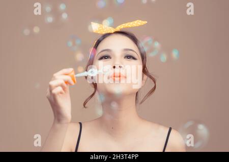 Felice bella donna soffiando bolle di sapone Foto Stock