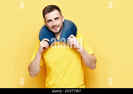 Giovane uomo con cuscino da viaggio su sfondo giallo Foto Stock