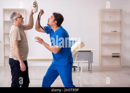 Vecchio paziente maschio incontro giovane medico maschio in medicina costosa Foto Stock