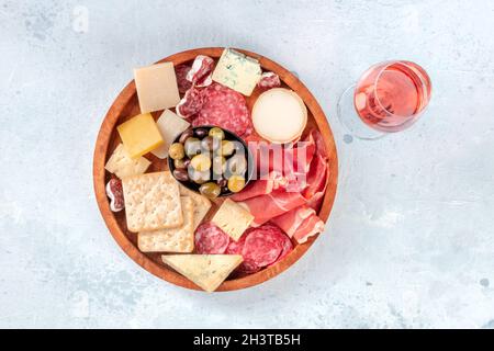 Salumi e tagliere di formaggi, sparati dall'alto con un bicchiere di vino rosato Foto Stock