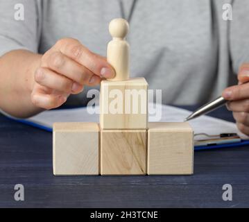 Cubi di legno nella forma di una scala e una figurina di un uomo. Concetto di crescita di carriera, obiettivo di realizzazione Foto Stock