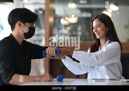 Fisioterapista femminile che lavora esaminando il trattamento del braccio ferito di paziente maschile. Foto Stock