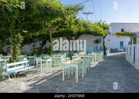 Grecia, isola di Folegandros. Tradizionale bar e taverna all'aperto. Tavoli e sedie blu vuoti, piazza della città di Chora. CICLADI. Vacanze estive destin Foto Stock