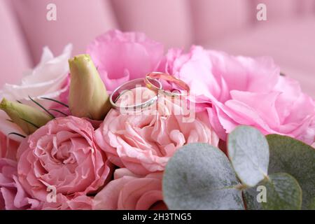 Due anelli di nozze di oro bianco e giallo su un bouquet di rose rosa. Foto Stock