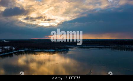 Vista aerea di un bellissimo e drammatico tramonto su un lago forestale riflesso nell'acqua, paesaggio fuco colpo Foto Stock