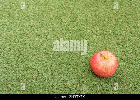 Faux mele rosse su erba sintetica. Per la coltivazione di mele nel Regno Unito, mele inglesi, industria britannica del sidro, ottobre Apple Day, prodotti britannici, uso di plastica Foto Stock