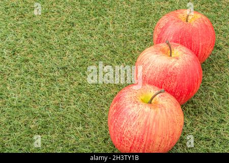 Faux mele rosse su erba sintetica. Per la coltivazione di mele nel Regno Unito, mele inglesi, industria britannica del sidro, ottobre Apple Day, prodotti britannici, uso di plastica Foto Stock