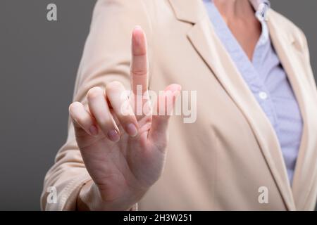 Sezione centrale di businessman caucasica che tocca l'interfaccia virtuale su sfondo grigio Foto Stock