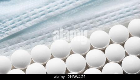 Righe di pillole e maschere mediche su sfondo bianco. Cura della salute, medicina, farmacia e concetto di malattia Foto Stock