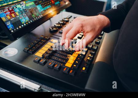 La mano del tecnico del suono sposta i cursori sulla console di mixaggio del suono durante lo spettacolo Foto Stock