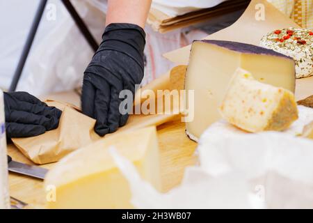 Formaggio di capra duro sul tavolo. Molte varietà di formaggi artigianali sono sul banco durante il festival del formaggio. Concetto di vendita di prodotti lattiero-caseari Foto Stock