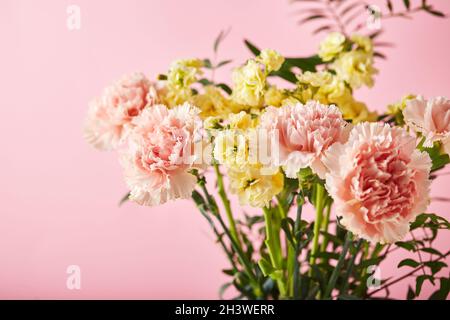 Bouquet di garofani rosa e mattiola gialla con rami verdi. Design concetto di saluto vacanza con bouquet garofano o Foto Stock