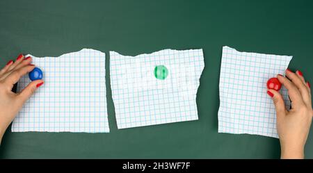Due mani femminili fissano fogli bianchi di carta in una scatola su un pannello magnetico verde Foto Stock