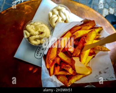 Serve tipiche patatine fritte belghe con salsa al tartufo e maionese Foto Stock