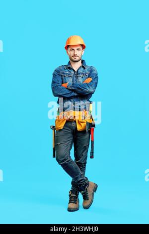 Ritratto a tutta lunghezza di sicuro bel lavoratore di costruzione maschile con braccia incrociate Foto Stock