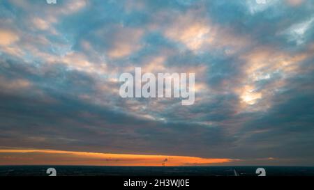 Tramonto con le nubi scure e drammatiche di tempesta di fondo che si dividono. La luce dal sole che tramonta la rende drammatica come colpisce Foto Stock