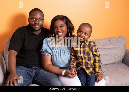 Bambino prescolare a casa con i genitori, in posa per ritratto di famiglia Foto Stock