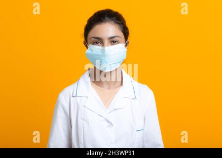 Ritratto di medico indiano donna in abito medico bianco isolato su sfondo giallo Foto Stock