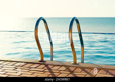 Scala in acciaio inossidabile in una piscina in un resort hotel Foto Stock