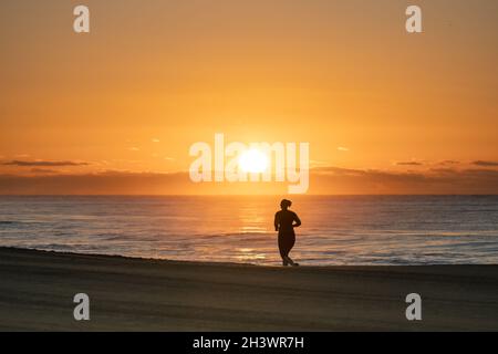 Alba a Meloeras, Gran Canaria con jogger sulla spiaggia Foto Stock