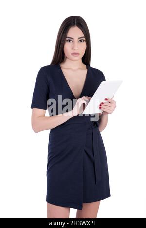 Giovane donna caucasica con lunghi capelli neri, vestita nera. Sta in piedi e sta tenendo una tavoletta. Foto Stock