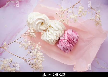 Sfondo femminile, marshmallow rosa e bianco con decorazione gypsofila primo piano. Weekend invernali accoglienti. Dolci fatti in casa. Vista dall'alto. Foto di alta qualità Foto Stock