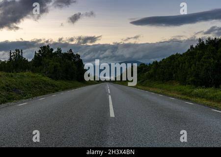 Vista ad angolo basso di una strada asfaltata che porta direttamente all'orizzonte in svedese Lappland Foto Stock