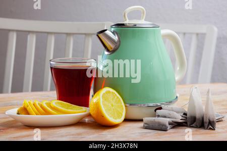 Bollitore elettrico moderno, tazza e limone sul tavolo in cucina Foto Stock