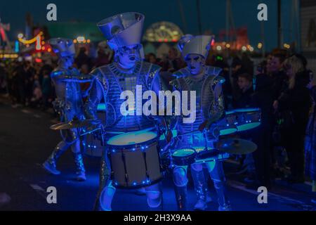30 ottobre 2021. Southend on Sea, Regno Unito. Un gruppo di batteristi illuminati in costumi metallici a tema spaziale si esibisce durante la sfilata di Halloween di Southend-on-Sea. I loro abiti argentati e i tamburi blu brillanti catturano gli spettatori che costeggiano il lungomare. La scena notturna include luci festive e una folla vivace. Penelope Barritt/Alamy Live News Foto Stock