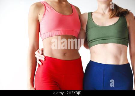 Due gioie donne felici in felpa con cappuccio rosa sportivo che prendono la pausa dopo le lezioni di yoga Foto Stock