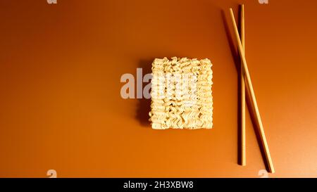 Tagliatelle secche crude con bacchette e spazio di copia. Cibo asiatico, minimalismo, pasta, per la preparazione di cui è eno Foto Stock