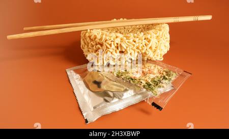 Spaghetti istantanei crudi con bacchette e spezie. Spazio copia cibo asiatico. Pasta, per la preparazione di cui è sufficiente versare Foto Stock