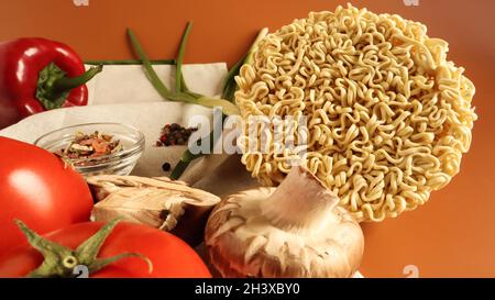 Spaghetti istantanei con funghi re, condimenti, salsa di soia, peperoni, cipolle verdi, pomodori. Zuppa vegetariana veloce di verdure. Il Foto Stock