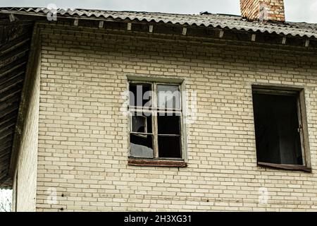 Una casa abbandonata con finestre rotte. Vecchio edificio in città. Struttura distrutta. Foto Stock