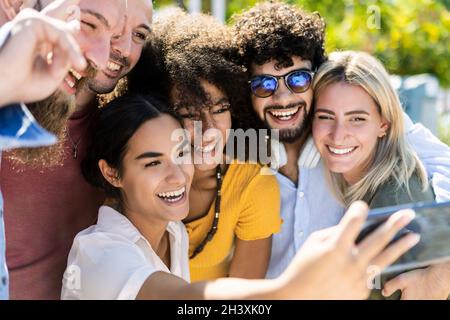 Gruppo multirazziale di giovani che prendono selfie con smartphone all'aperto Foto Stock