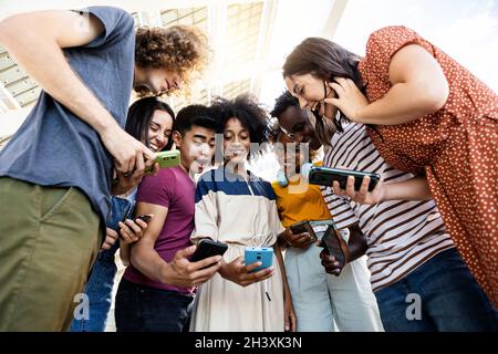 Gruppo di persone multirazziali che utilizzano il cellulare all'aperto Foto Stock