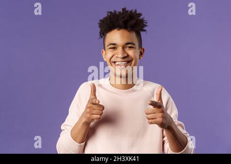 Hai capito. Primo piano ritratto di sorridente simpatico giovane ispanico che dice buona fortuna, puntando le dita verso la fotocamera con piacere cute Foto Stock