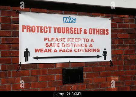 Un segnale di distanza di sicurezza NHS Covid su un muro in Sussex, Regno Unito. Foto Stock