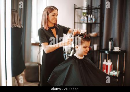 Professionale sicuro sorridente donna hairstylist preparare cliente femmina per taglio di capelli Foto Stock
