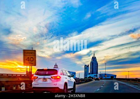 Il sole tramonta sulla Città di Mobile mentre il traffico dell'Interstate 10 si dirige verso ovest sulla Mobile Bayway, 23 ottobre 2021, a Mobile, Alabama. Foto Stock