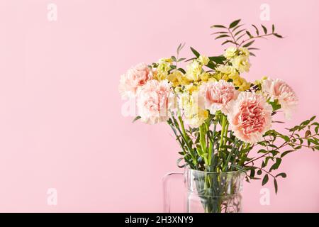 Bouquet di garofani rosa e mattiola gialla con rami verdi. Design concetto di saluto vacanza con bouquet garofano o Foto Stock