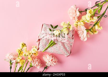 Bouquet di garofani rosa e mattiola gialla con confezione regalo in stile tradizionale giapponese furoshiki. Design concetto di vacanza Foto Stock